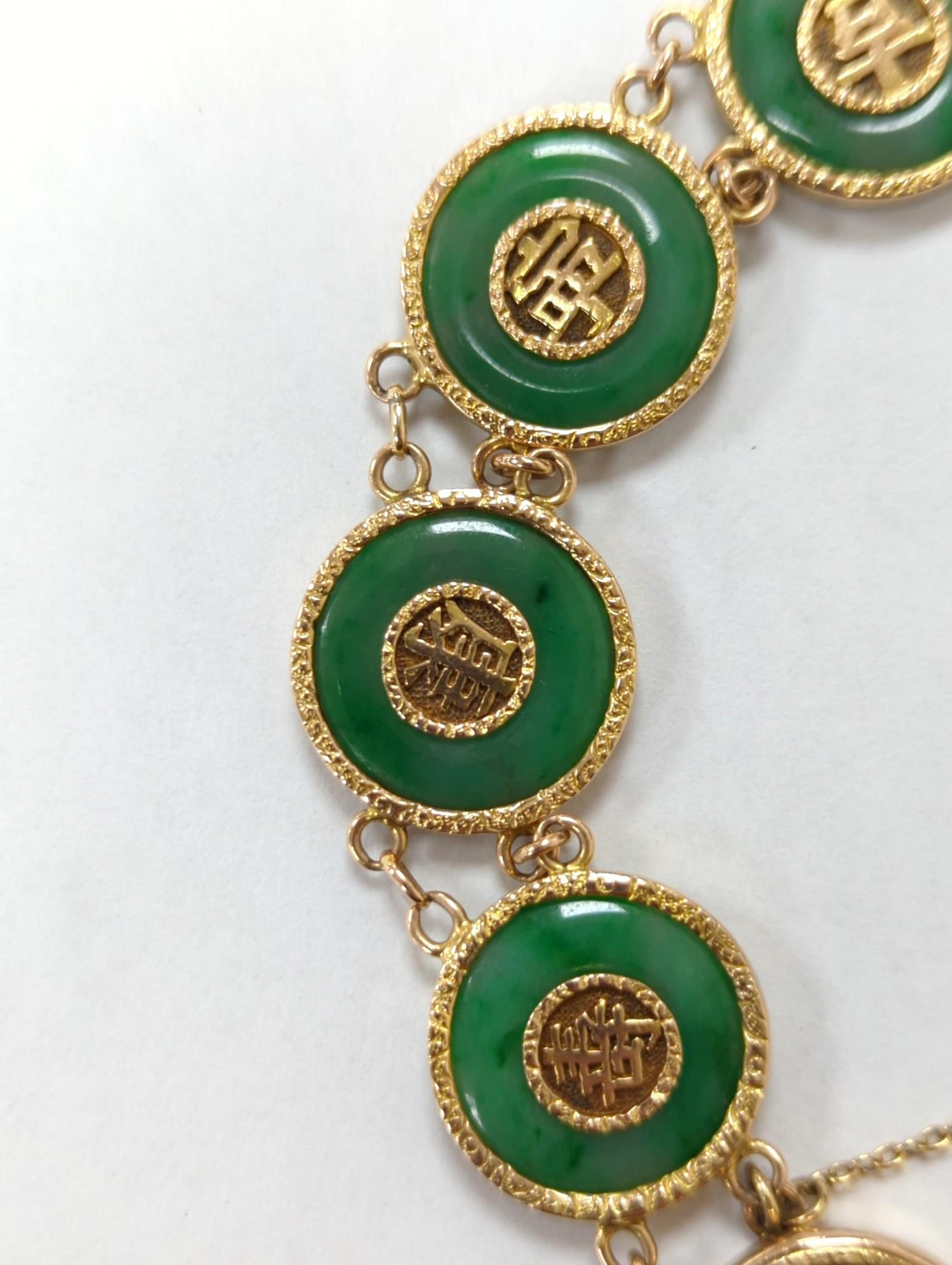 A Chinese yellow metal (stamped 18) and pierced eight stone jade disc set bracelet, with central Chinese characters, 16.5cm approx. gross weight 27.7 grams.